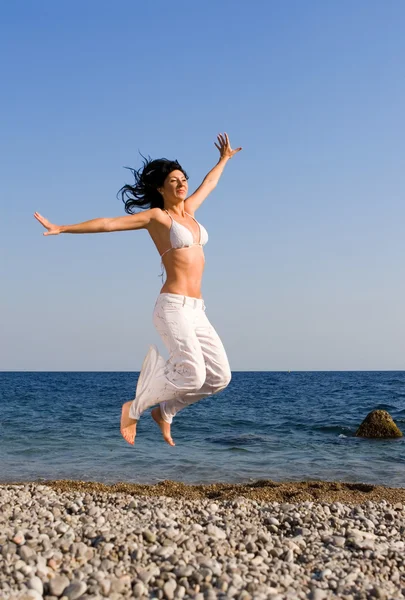 Glückliche junge Frau springt in den Strand — Stockfoto