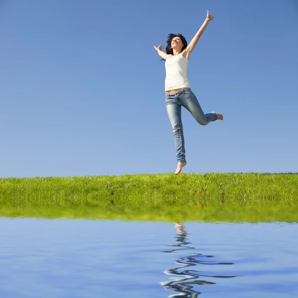 Mooie jonge vrouw springen op groen gras — Stockfoto