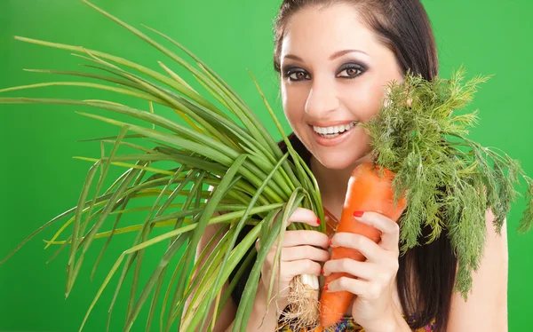 Красивая девушка с морковкой и луком на зеленом фоне — стоковое фото