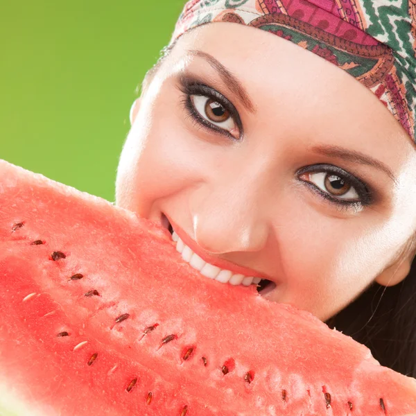 Modefrau beißt rote Wassermelone auf grünem Hintergrund — Stockfoto