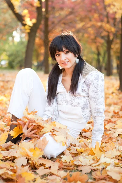 Junge hübsche Frau ruht sich im Herbstpark aus — Stockfoto