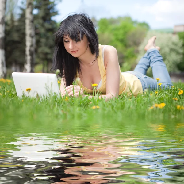 Cute woman with white laptop in the park with dandelions — Stock Photo, Image