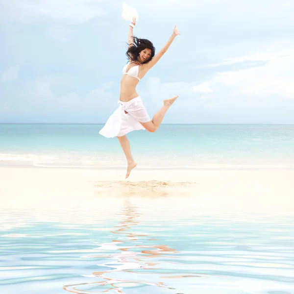 Happy young woman jumping on the beach of sea — Stock Photo, Image