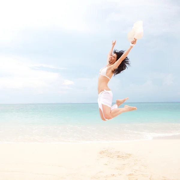 Счастливая молодая женщина прыгает на пляже — стоковое фото