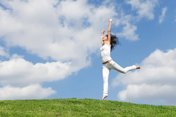 Genç ve güzel kadın yeşil çimenlerin üzerinde atlama — Stok fotoğraf