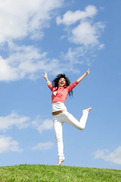Genç ve güzel kadın yeşil çimenlerin üzerinde atlama — Stok fotoğraf