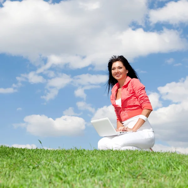 Roztomilá žena s bílým laptop v parku — Stock fotografie