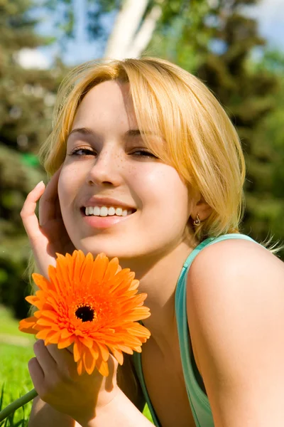Vacker kvinna resten i parken med blomma — Stockfoto