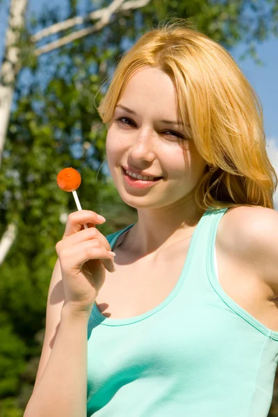 Junge Blondine leckt Bonbons im Park — Stockfoto