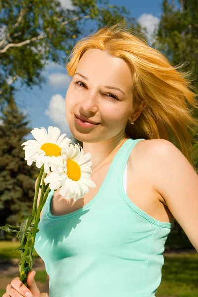 Leuke vrouw rust in het park met bloemen — Stockfoto
