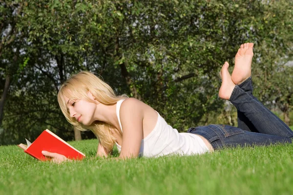 Junge Blondine liest Buch im Park — Stockfoto