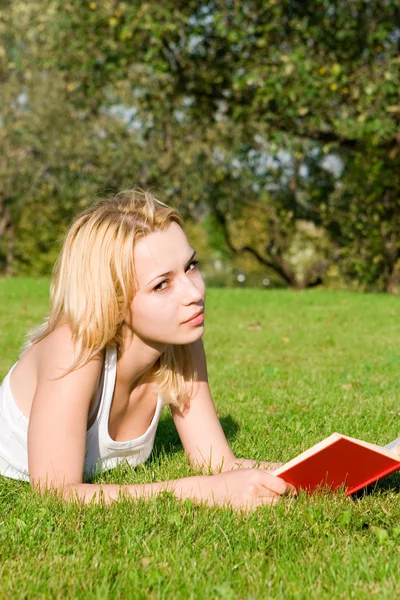 Młoda blondynka czyta książkę w parku — Zdjęcie stockowe