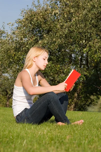 Giovane bionda legge libro nel parco — Foto Stock