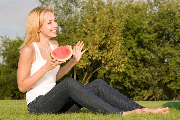 Unga blonda äter vattenmelon i parken — Stockfoto