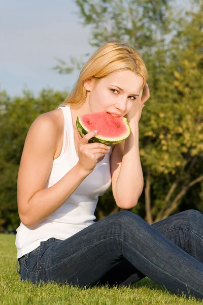 Young blonde eats watermelon in the park — Stock Photo, Image
