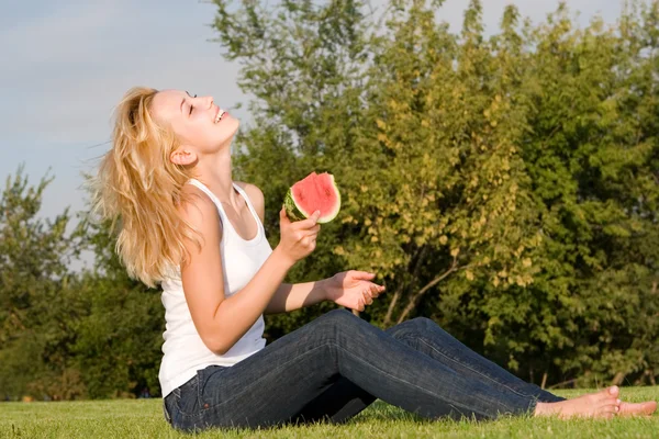 Jovem loira come melancia no parque — Fotografia de Stock