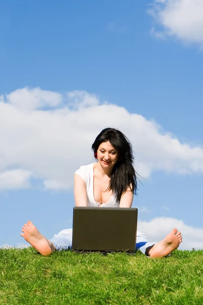 Pretty woman with laptop on the green grass Stock Picture