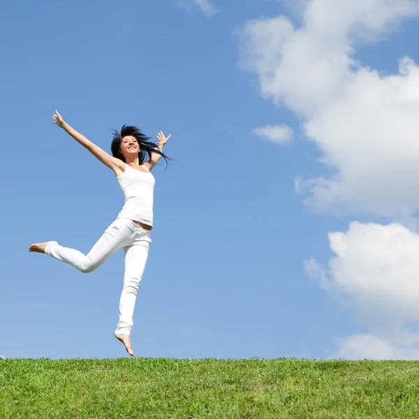 Красива молода жінка стрибає на зеленій траві Стокове Фото