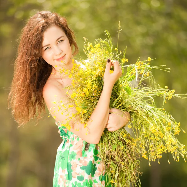 Jeune rousse femme dans le parc avec des fleurs — Photo