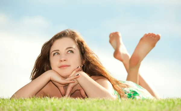 Jonge vrouw rust op het groene gras — Stockfoto