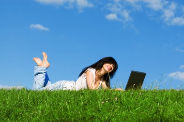 Yeşil çimenlerin üzerinde laptop ile güzel kadın