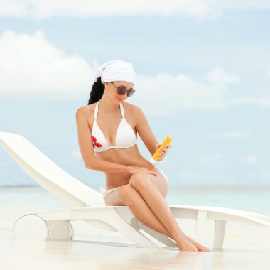 Young woman with sun-protection cream on the beach clipart