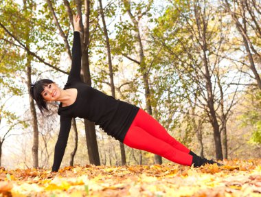 güzel bir kadın yoga egzersizleri sonbahar Park yapıyor