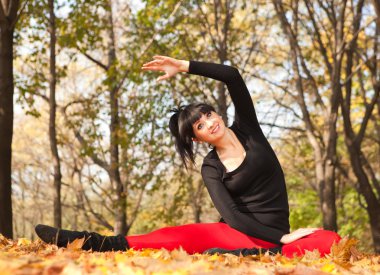 güzel bir kadın yoga egzersizleri sonbahar Park yapıyor