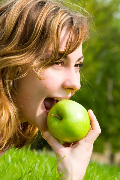 Όμορφη γυναίκα τρώει πράσινο μήλο σε ξέφωτο καλοκαίρι — Φωτογραφία Αρχείου