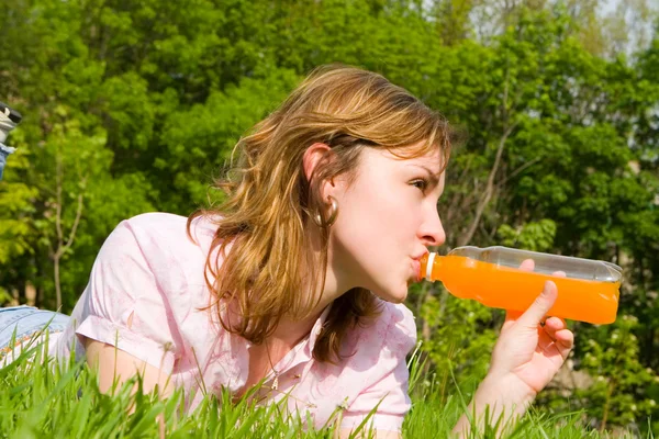 Красивая женщина пьет сок на летней поляне — стоковое фото