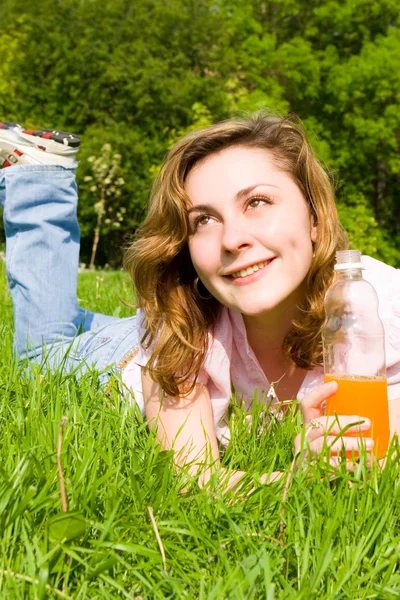 Pretty woman drinking juice on the summer glade — Stock Photo, Image