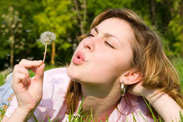 Happy girl blowing on the dandelion — Stock Photo, Image