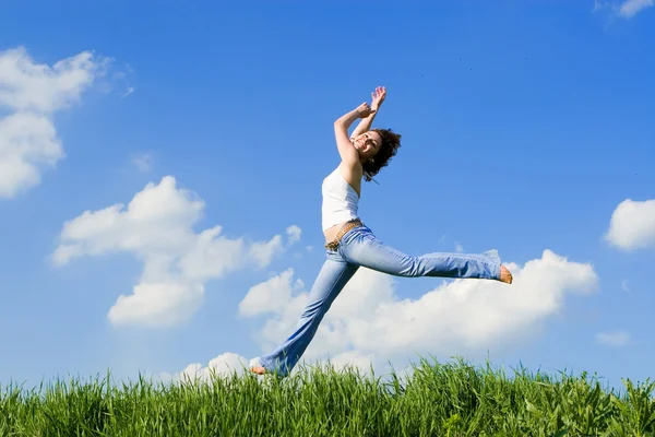 Szczęśliwa młoda kobieta skoki w zielonej trawie — Zdjęcie stockowe