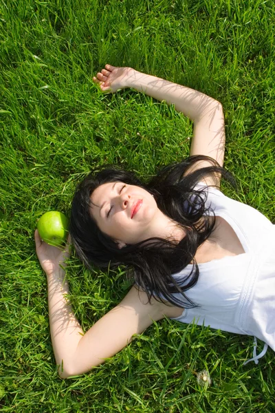 Mujer bonita comiendo manzana verde en el glade de verano — Foto de Stock