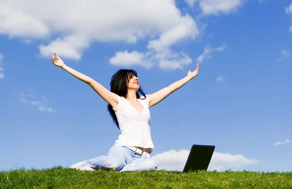 Mooie vrouw met laptop op het groene gras — Stockfoto