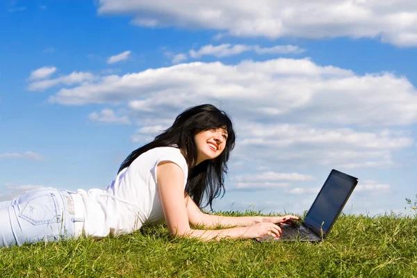 Mooie vrouw met laptop op het groene gras — Stockfoto