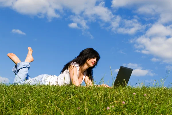 Krásná žena s laptopem na zelené trávě — Stock fotografie
