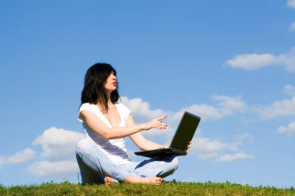 Mujer bonita con el ordenador portátil en la hierba verde —  Fotos de Stock