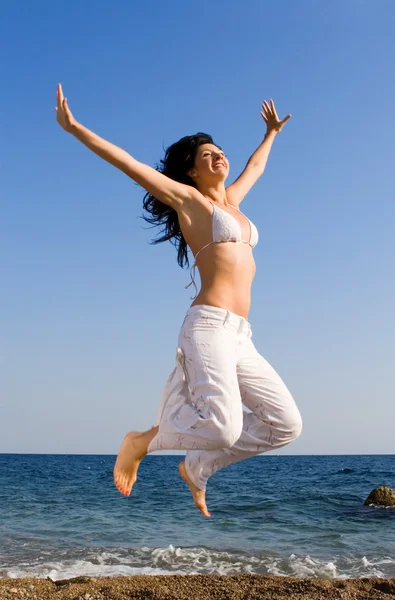 Glückliche junge Frau springt in den Strand — Stockfoto