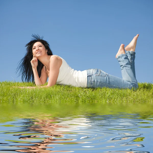 Šťastná mladá žena odpočinku na zelené trávě — Stock fotografie