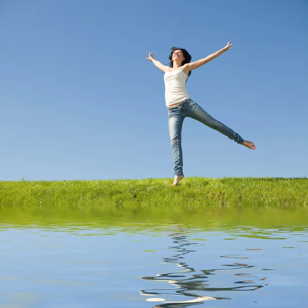 漂亮的年轻女人在绿草地上跳跃 — 图库照片