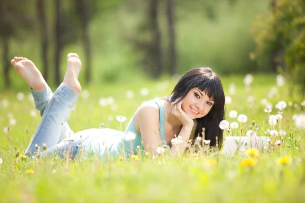 白いラップトップ タンポポと公園でかわいい女 — ストック写真