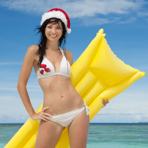 Happy santa woman with inflatable mattress on the beach — Stock Photo, Image