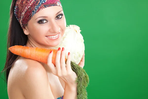 有胡萝卜和卷心菜的绿色背景上的漂亮女孩 — 图库照片