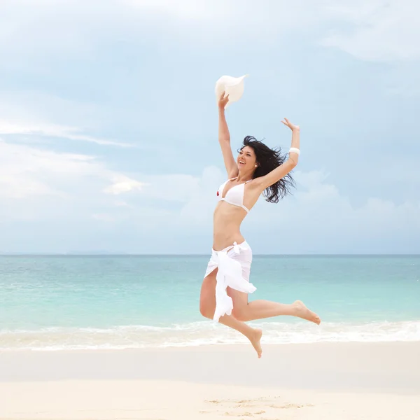Joyeux jeune femme sautant sur la plage — Photo