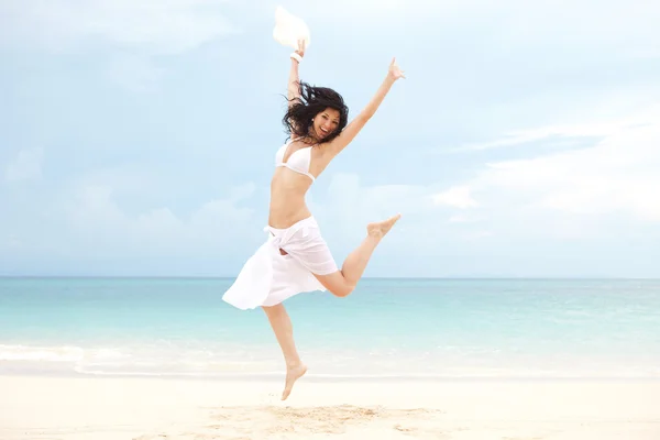 Glückliche junge Frau springt am Strand des Meeres — Stockfoto