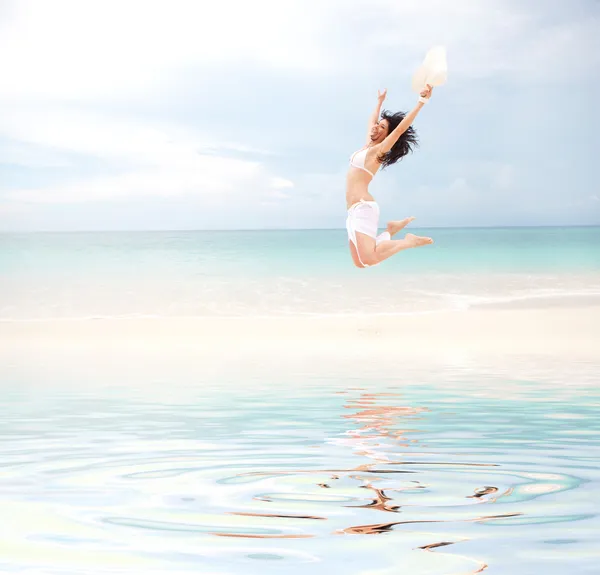 Щаслива молода жінка стрибає на пляжі — стокове фото