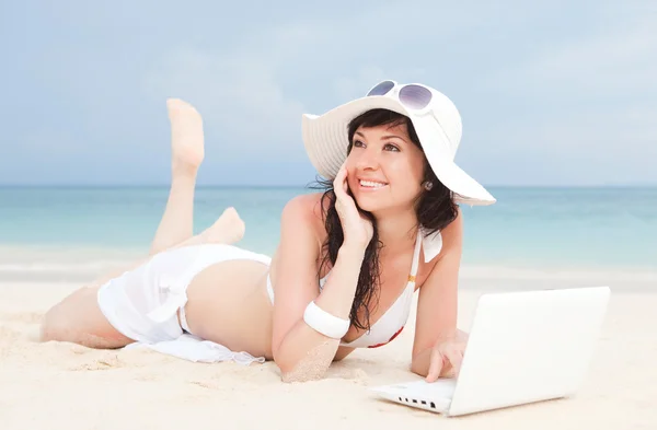 Femme mignonne avec ordinateur portable blanc sur la plage d'été — Photo