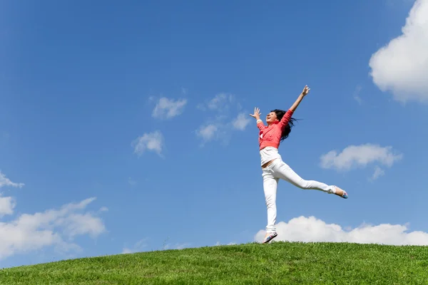 Pretty young woman jumping on green grass — Stock Photo, Image