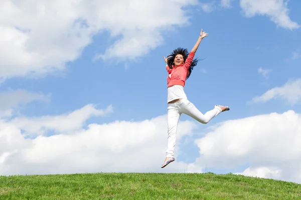 Mulher muito jovem pulando na grama verde — Fotografia de Stock